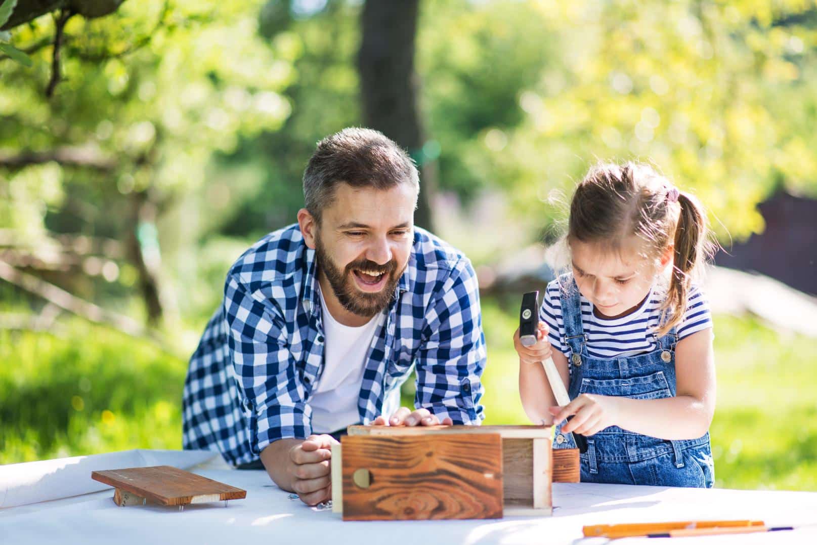 father-with-a-small-daughter-outside-making-wood